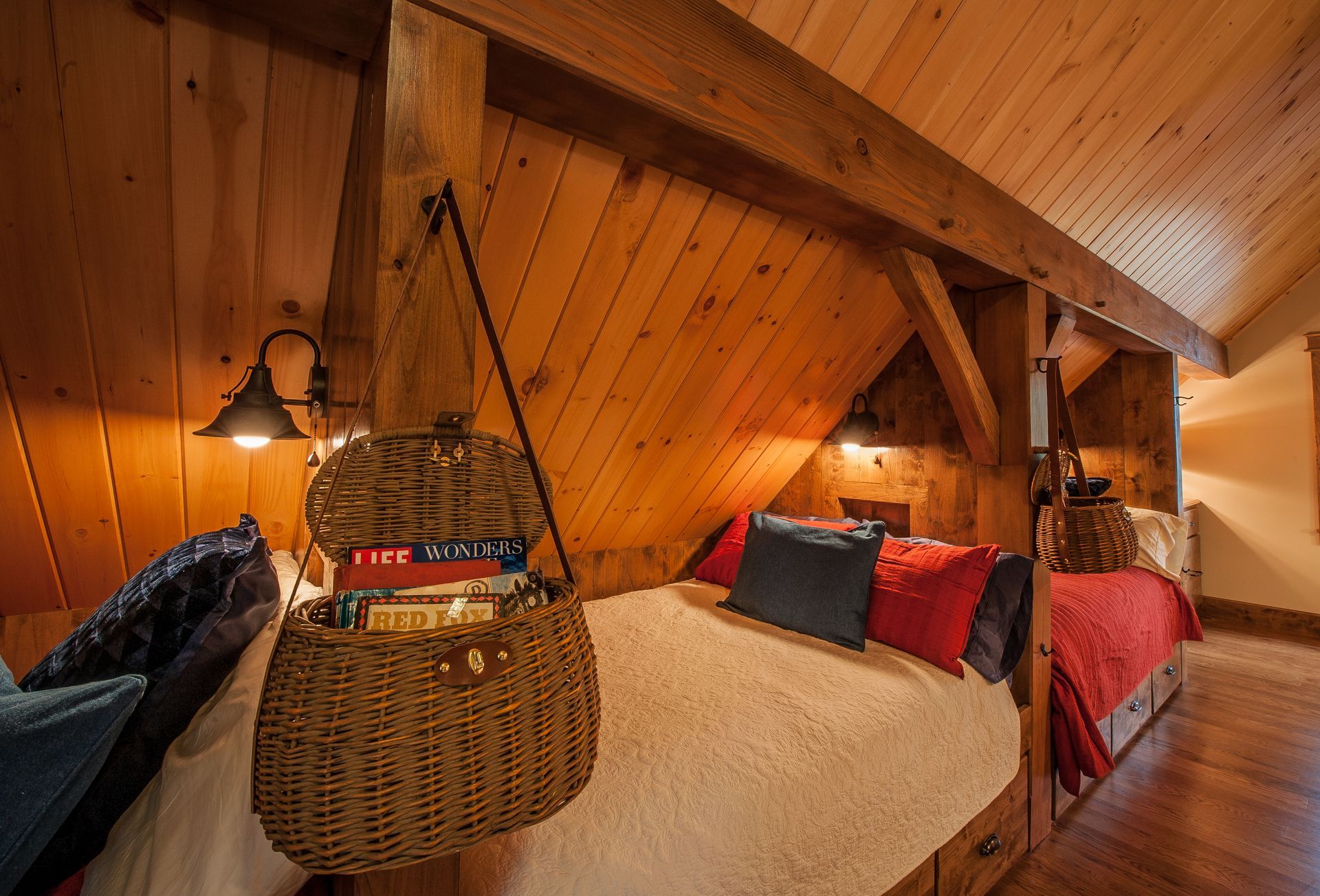 Cozy, wood-paneled bedroom with two beds in alcoves. Wicker basket hangs between beds.