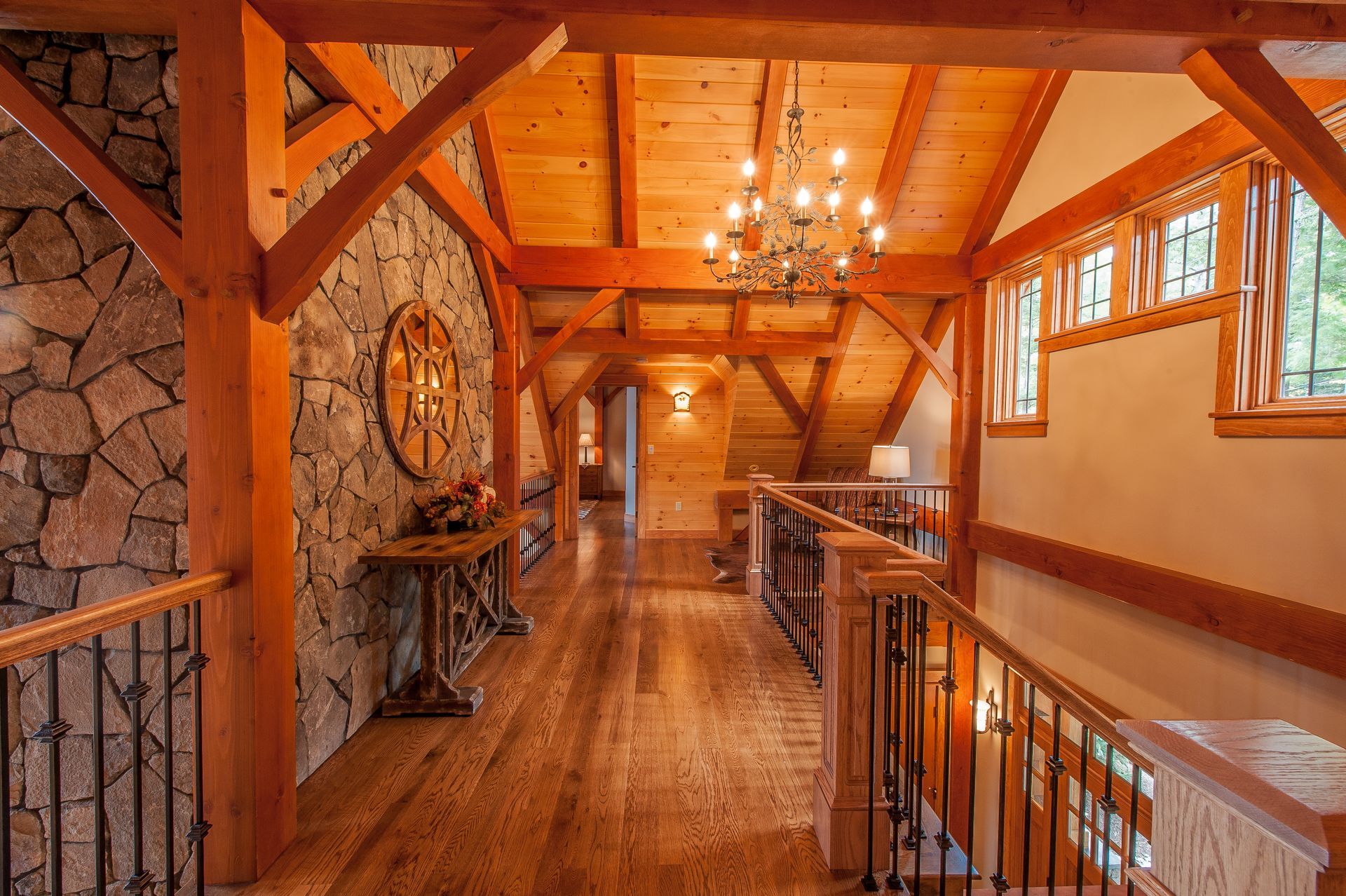 Hallway with wood beams, stone wall, and chandelier.