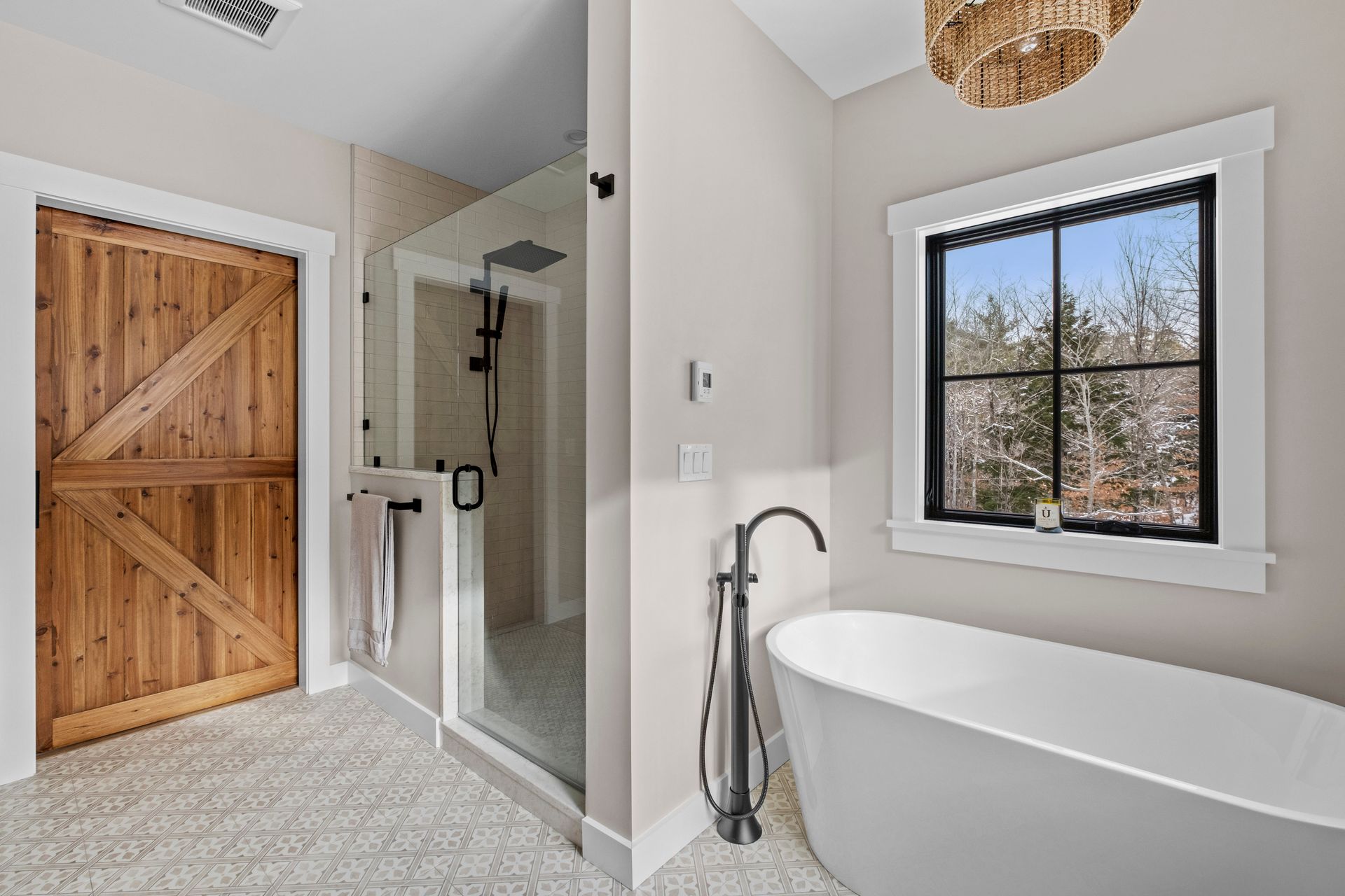 Bathroom with a wooden door, glass shower, and freestanding white bathtub.