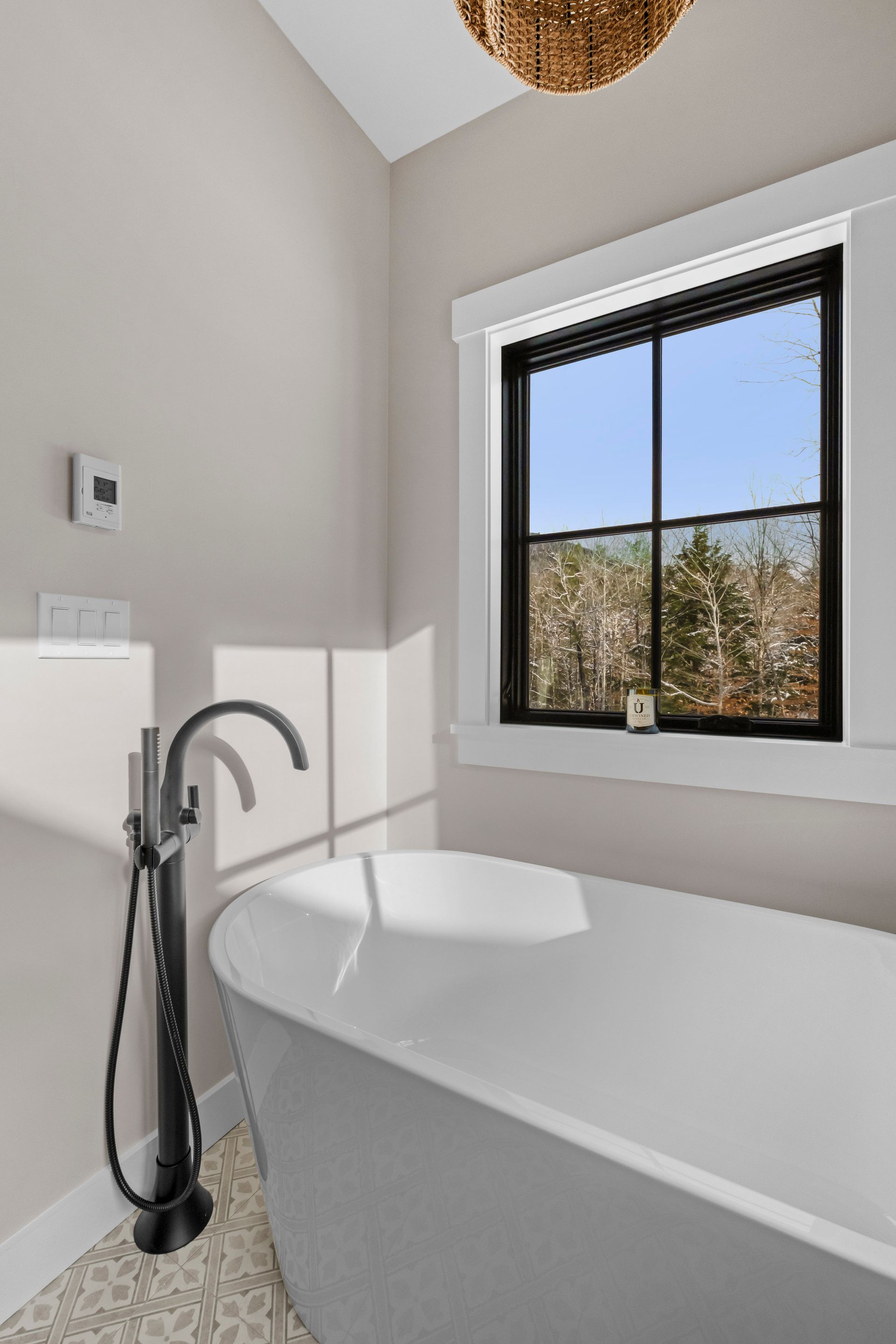 Bathroom with white tub, black faucet, and window with outdoor view.