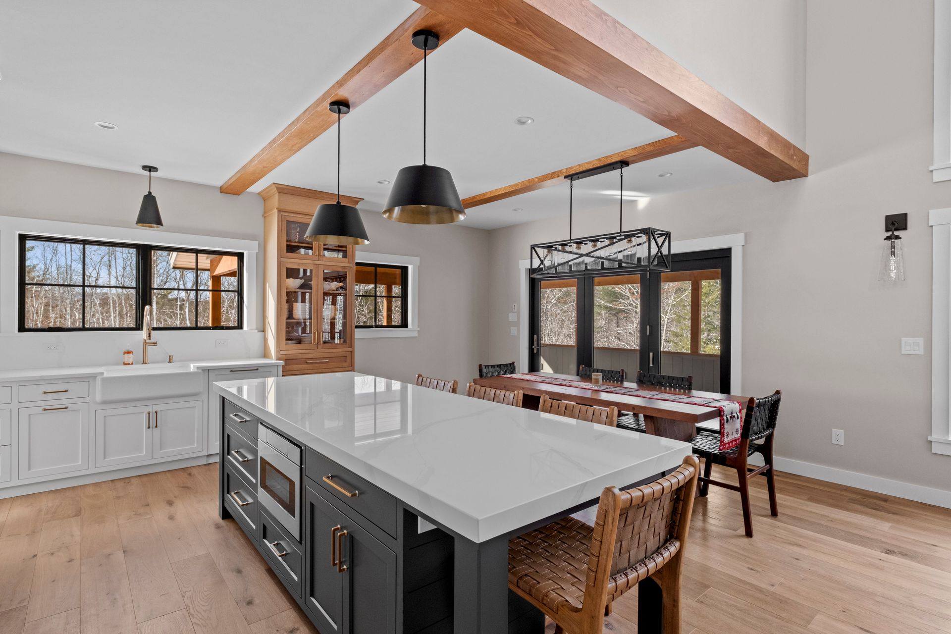Spacious kitchen with a large island, wooden beams, and a dining area, featuring natural light and a modern design.