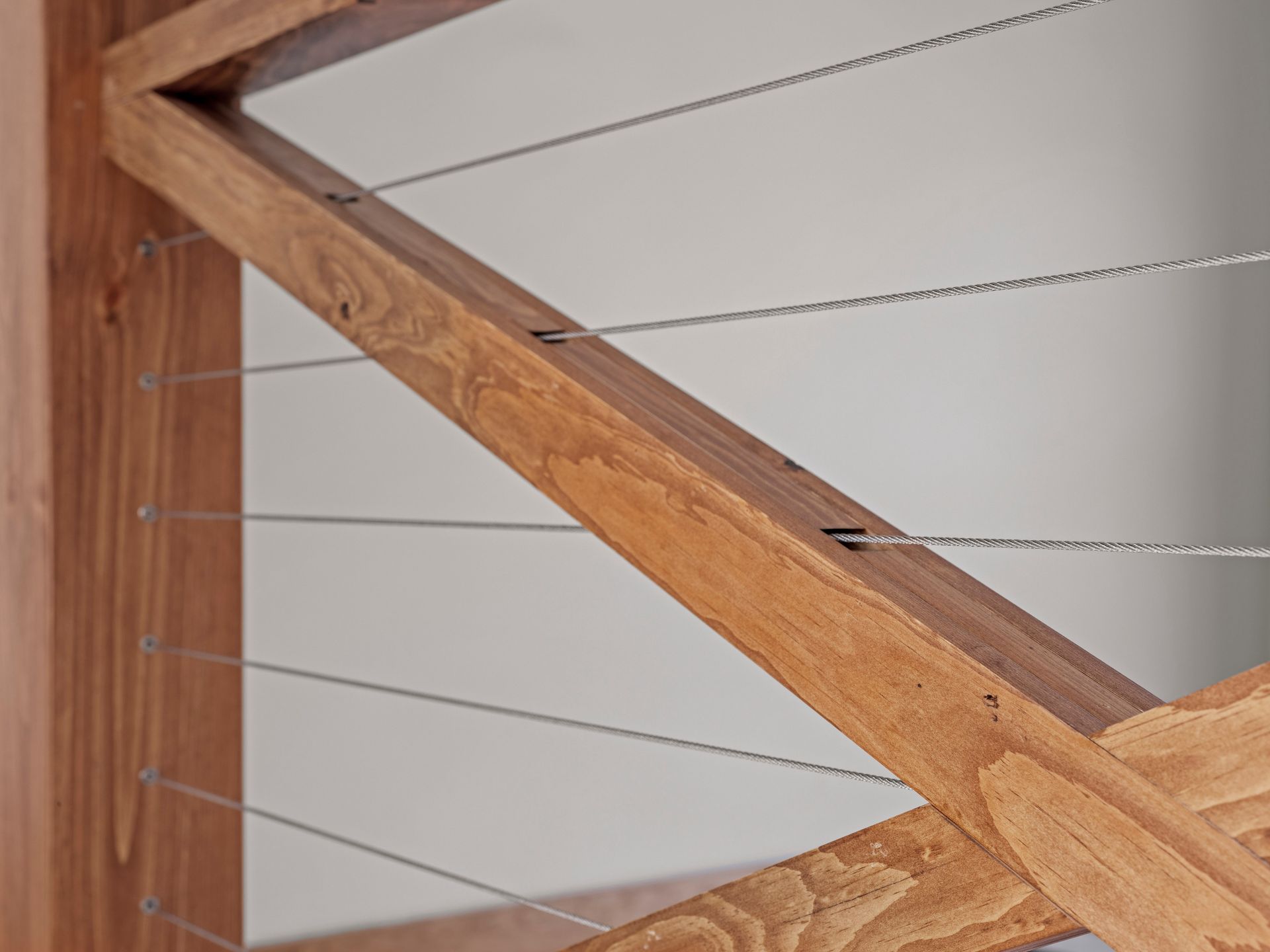 Wooden railing with stainless steel cables, close-up view.
