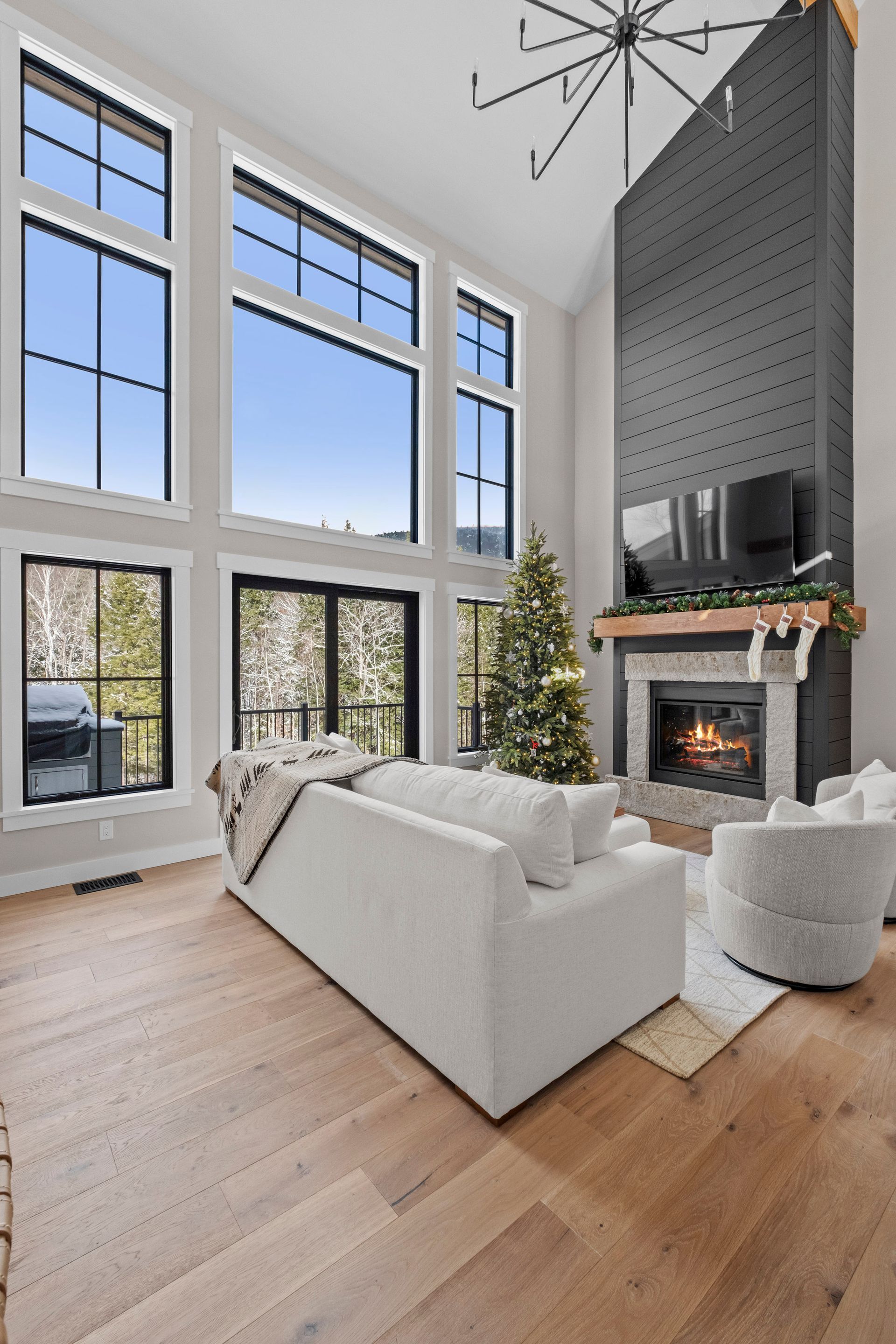 Living room with large windows, fireplace, white sofa, and Christmas tree.