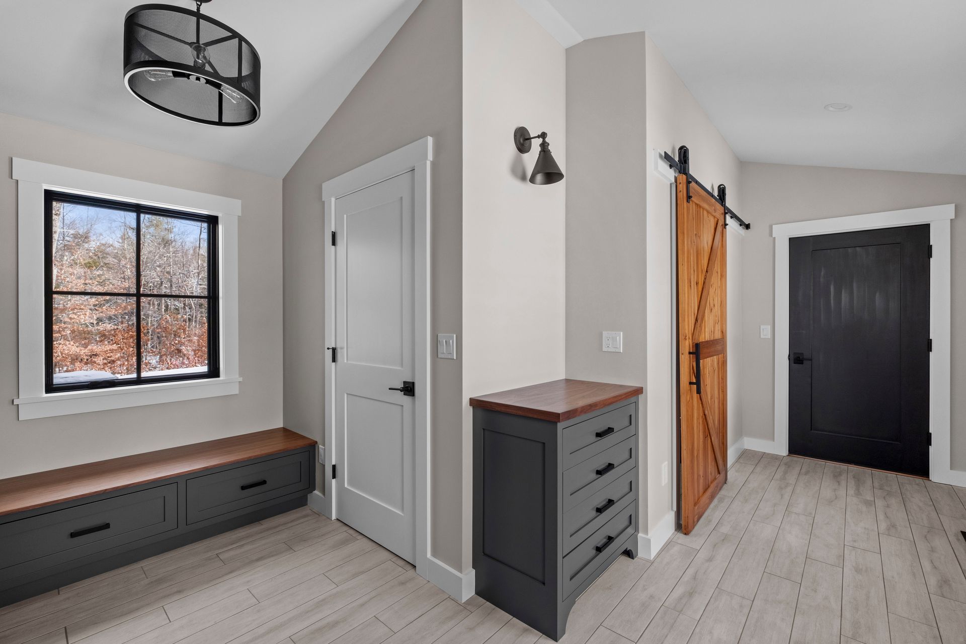Hallway with a wooden barn door, a gray bench, and a dark cabinet.