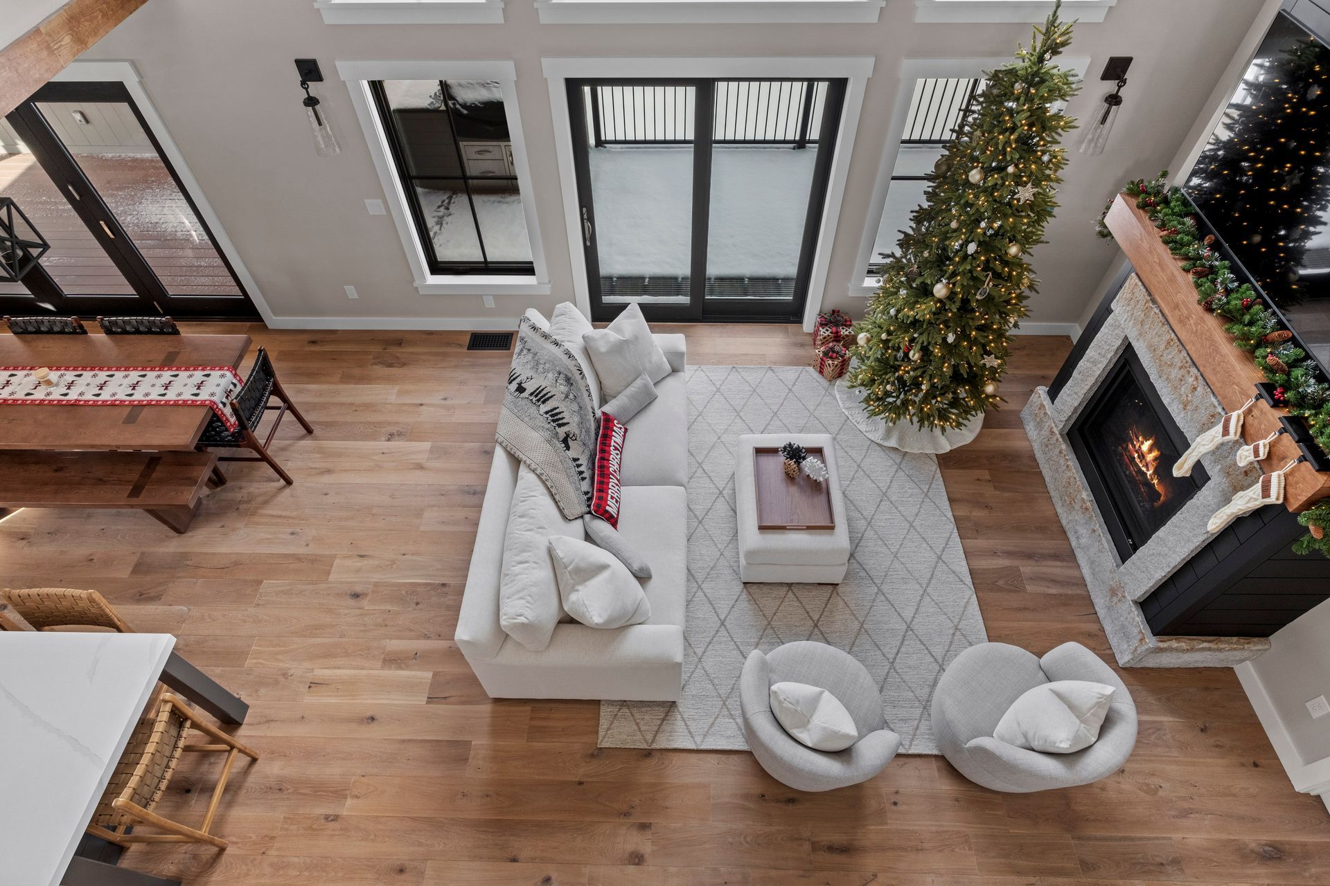 High-angle view of a modern living room with a Christmas tree, fireplace, and seating area.