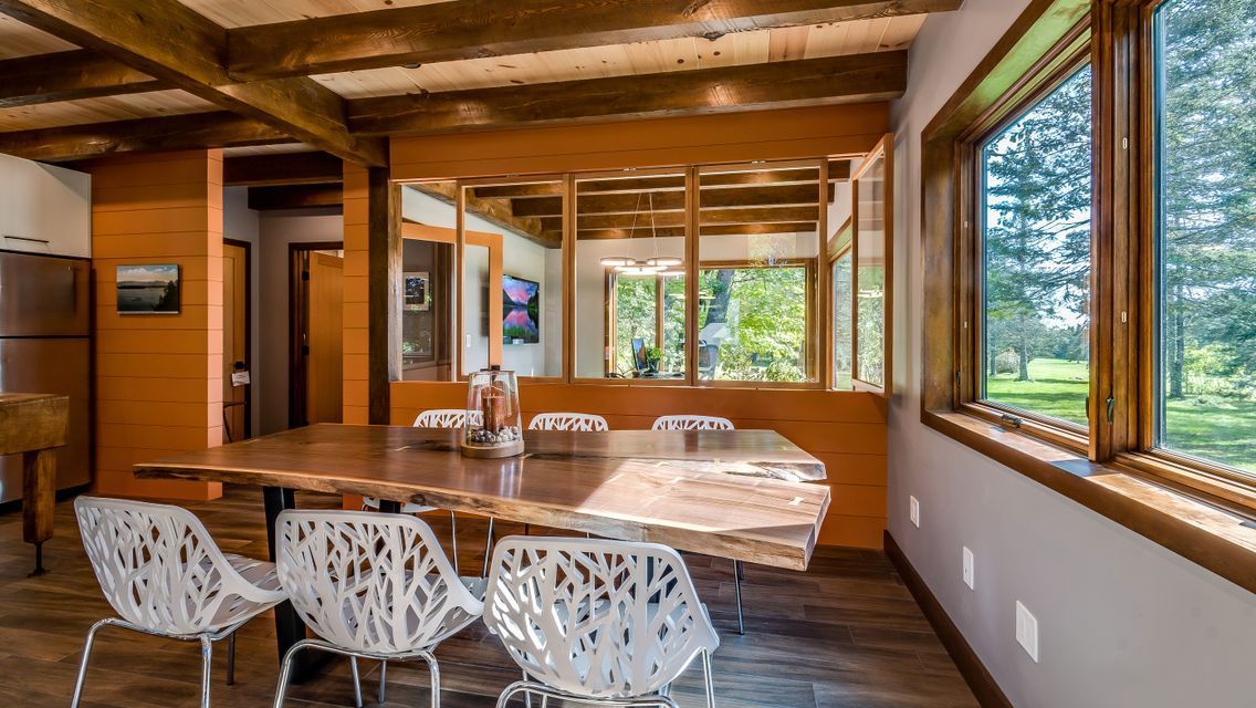 A dining room with a table and chairs and a lot of windows.