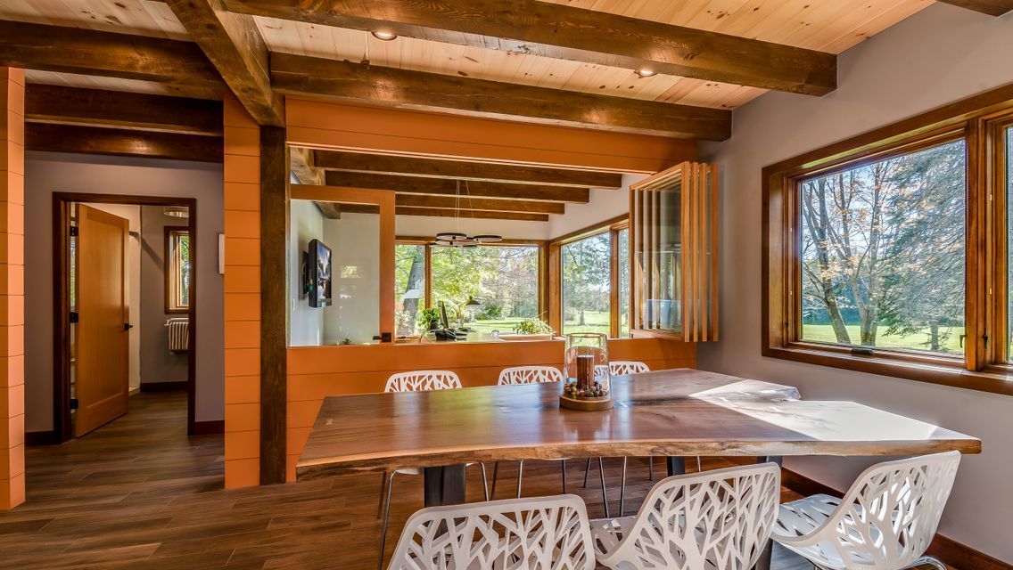 A dining room with a wooden table and chairs and a lot of windows.