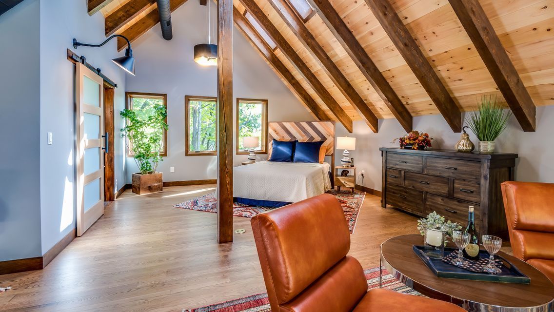 A living room with a bed , chairs , a table and a dresser.