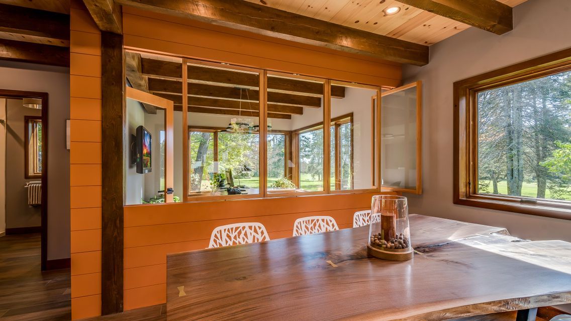 A dining room with a table and chairs and a lot of windows.