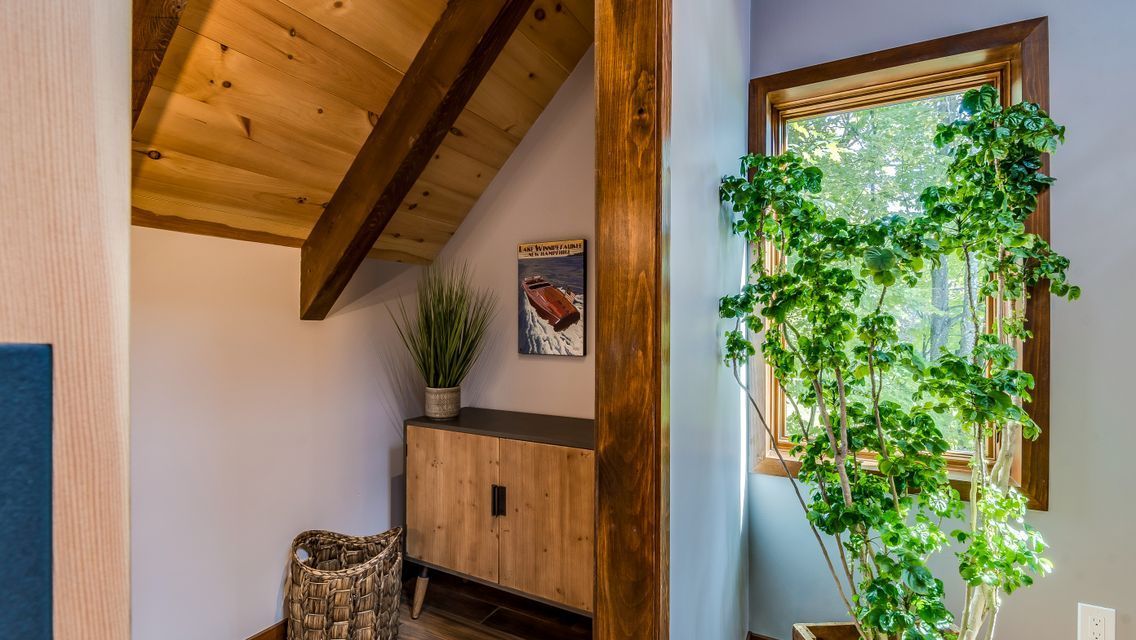 A room with a wooden ceiling and a window with a plant in it.