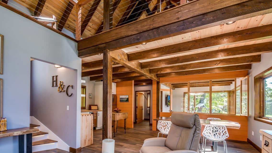 A living room with a couch and stairs in a house with wooden beams.