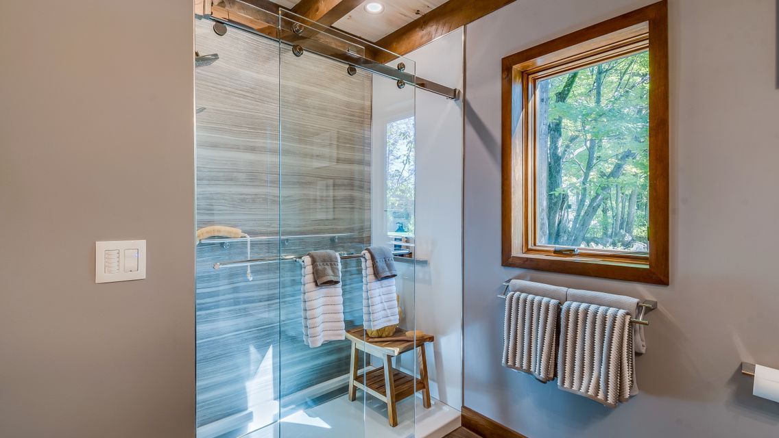 A bathroom with a walk in shower and a window.
