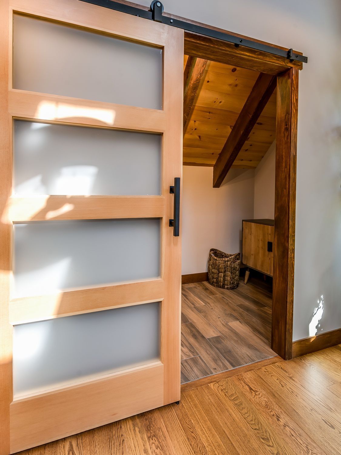 A sliding barn door is open to a room with hardwood floors.