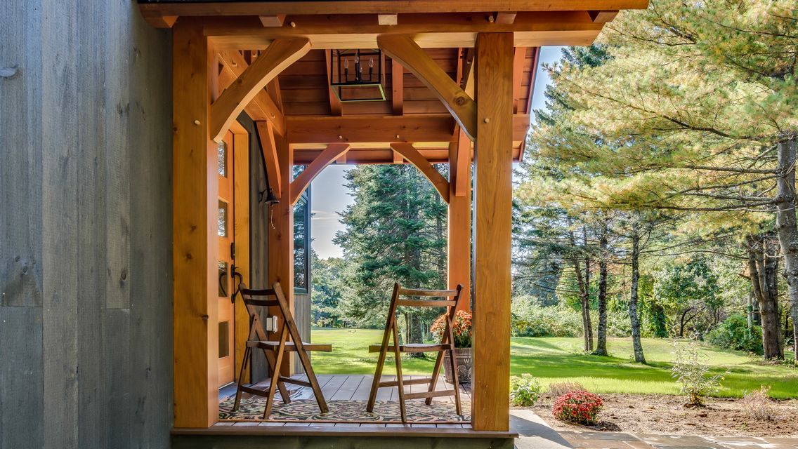 A wooden porch with chairs and a ladder in front of a house.