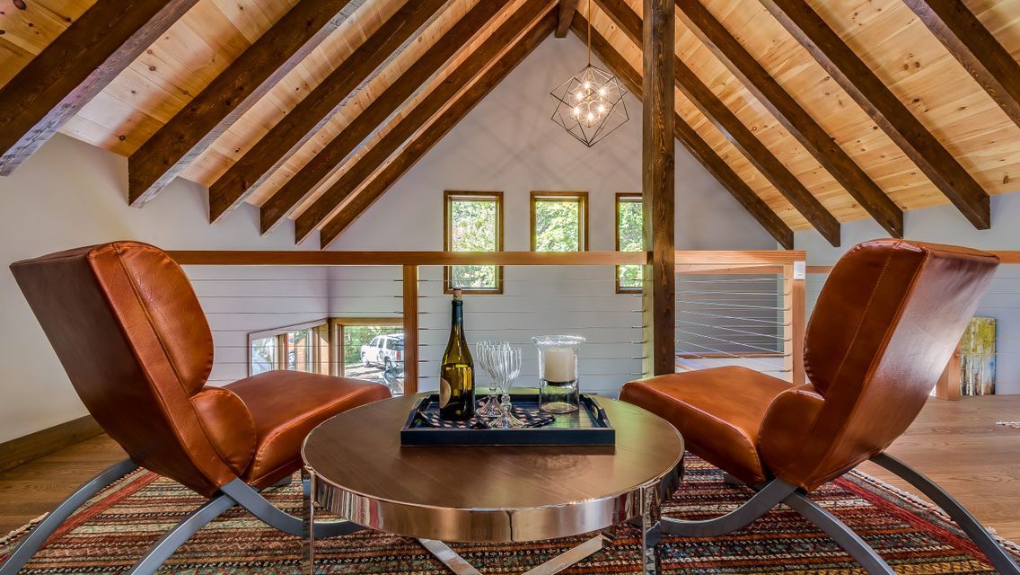 A living room with two chairs and a table with a bottle of wine on it.