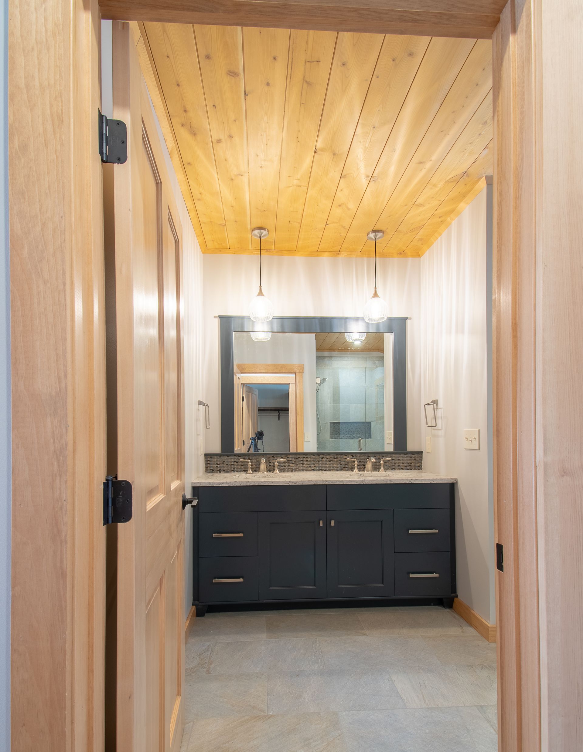 A bathroom with two sinks , a mirror and a wooden ceiling.