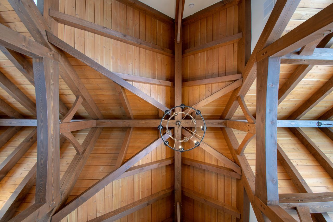 Looking up at the ceiling of a wooden building with a chandelier hanging from it.