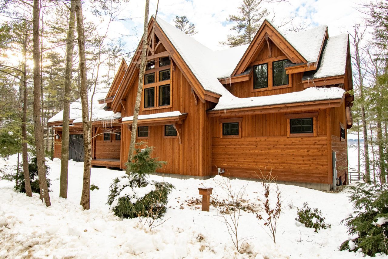 A large wooden house in the middle of a snowy forest.