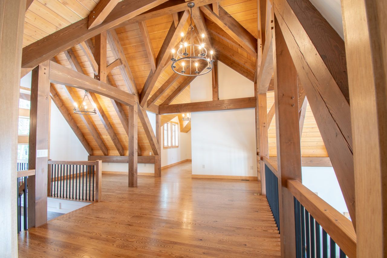 A large empty room with wooden beams and a chandelier hanging from the ceiling.