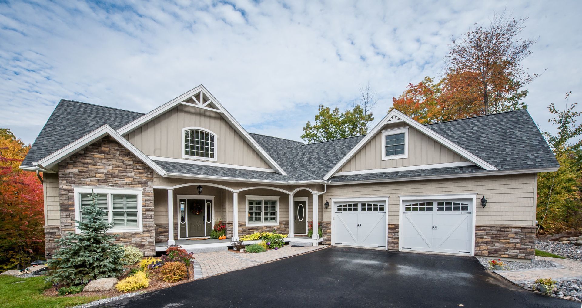 A large house with two garages and a driveway in front of it.