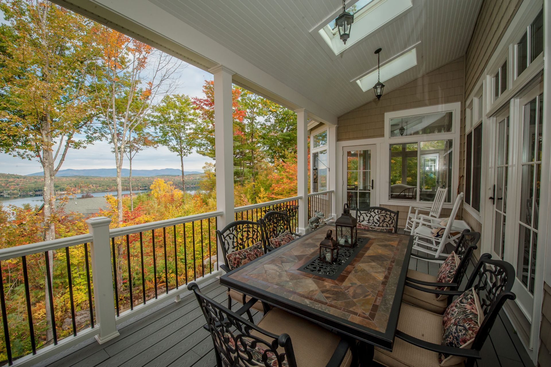 A porch with a table and chairs and a view of a lake.
