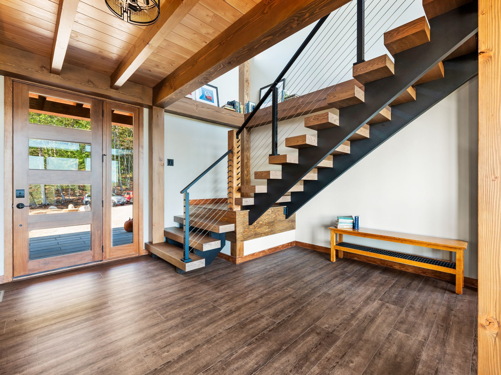 Modern entryway with dark wood floors, a natural wood ceiling, a glass front door, and a floating staircase.