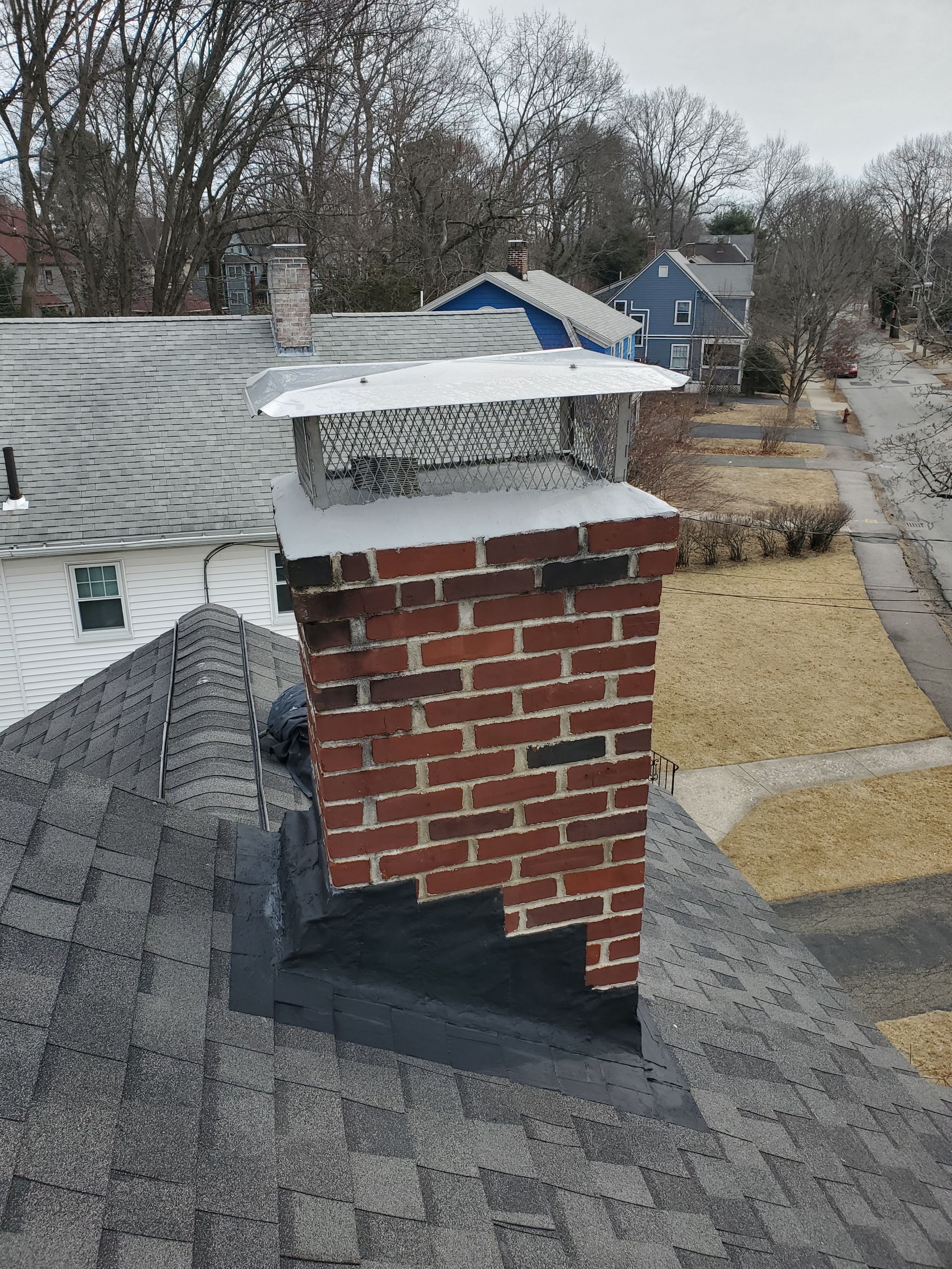 A brick chimney is sitting on top of a roof.