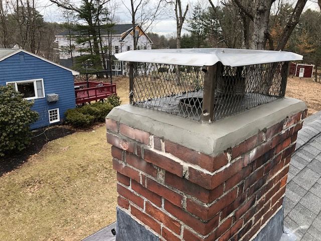 A brick chimney on top of a roof next to a blue house.