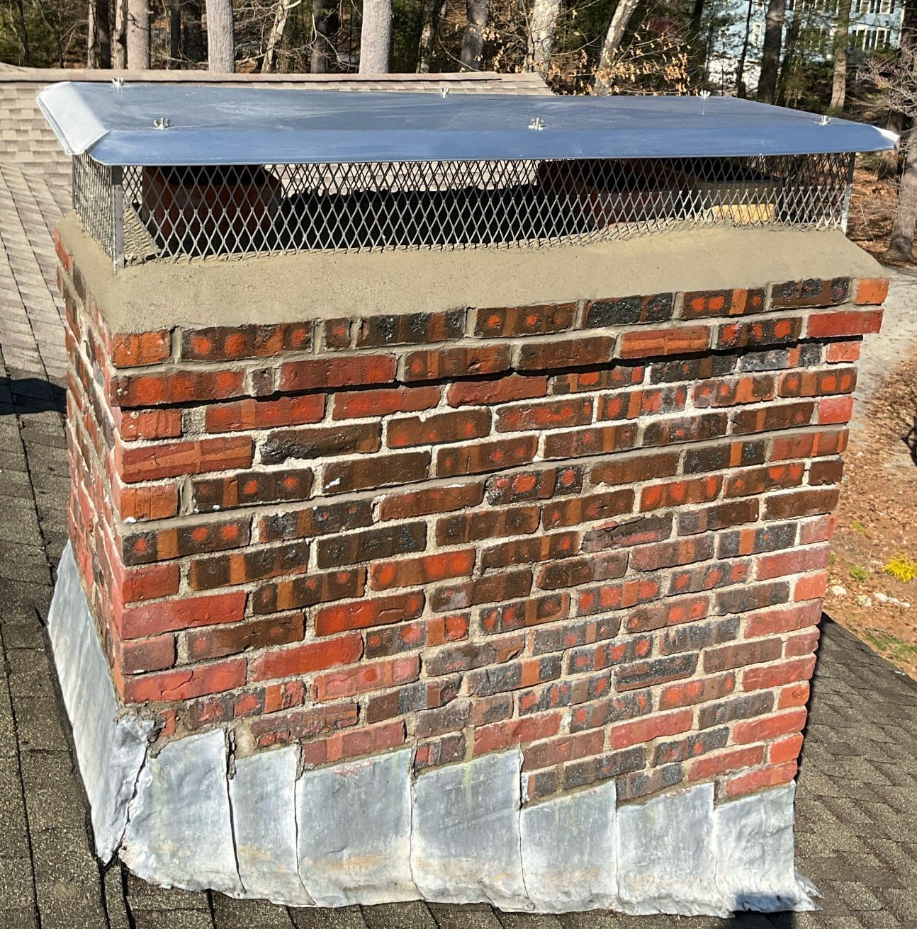 A brick chimney with a metal cover on top of it
