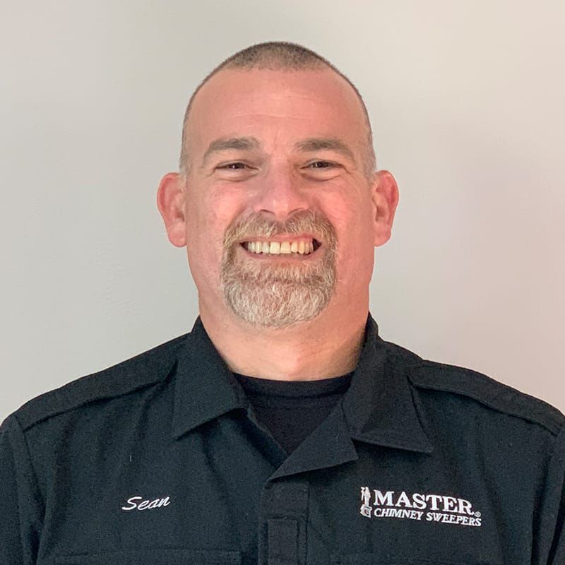 A man with a beard is wearing a black shirt and smiling.