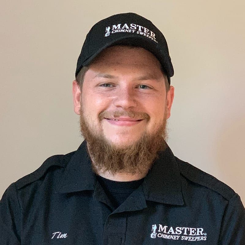 A man with a beard is wearing a black hat and smiling.