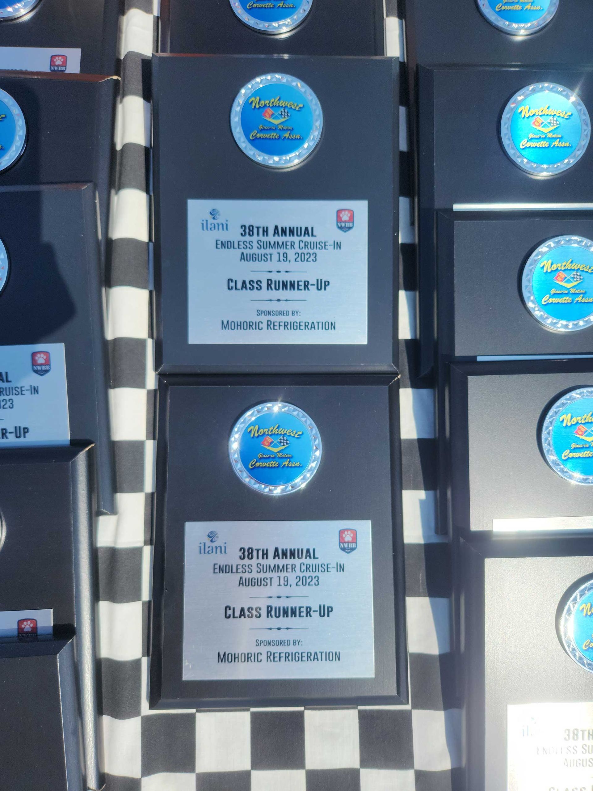 Awards on a checkered surface, plaques with silver lettering. Plaques say “Class Runner Up”.