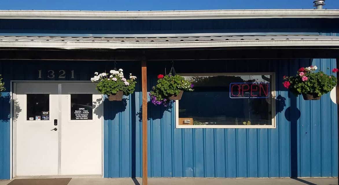 Blue building with white door and window, hanging flower baskets, 