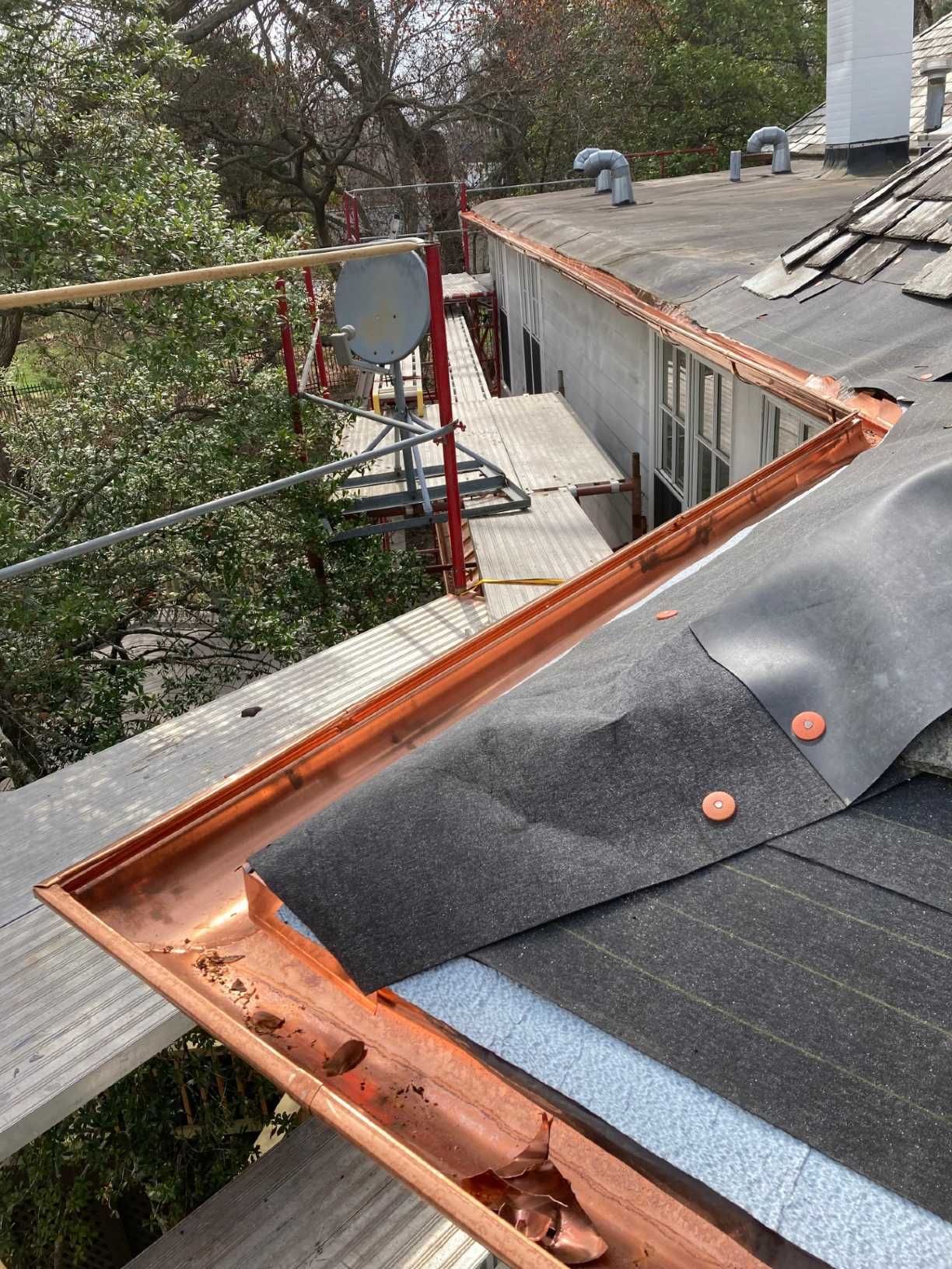 A close up of a roof with a copper gutter on it.