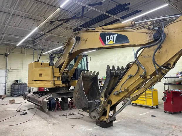 Yellow Caterpillar excavator inside a garage.
