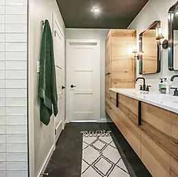 A bathroom with two sinks , a mirror , and a rug.