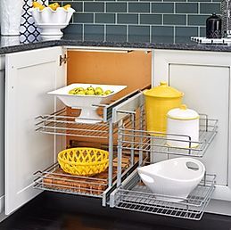 A kitchen cabinet with a basket, bowls, pots and pans in it.