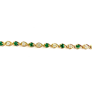 A gold bracelet with emeralds and diamonds on a white background