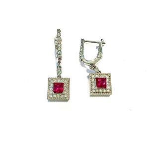 A pair of earrings with red stones and diamonds on a white background.