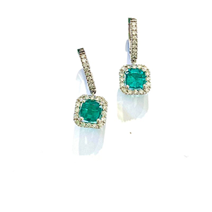 A pair of earrings with emeralds and diamonds on a white background.