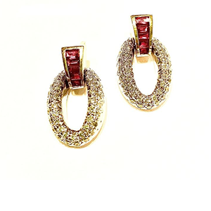 A pair of gold earrings with red stones on a white background