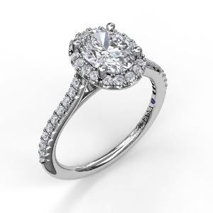 A white gold engagement ring with an oval diamond in the center surrounded by smaller diamonds.