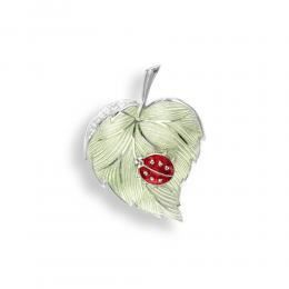 A brooch in the shape of a leaf with a ladybug on it.