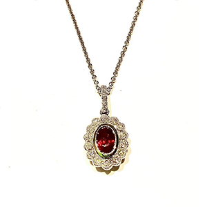 A necklace with a red stone and diamonds on a chain