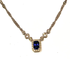 A necklace with a sapphire and diamonds on a white background
