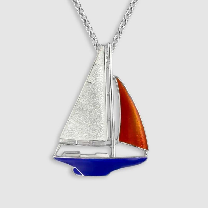 A silver necklace with a red sailboat pendant
