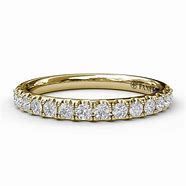 A yellow gold wedding band with diamonds on a white background.