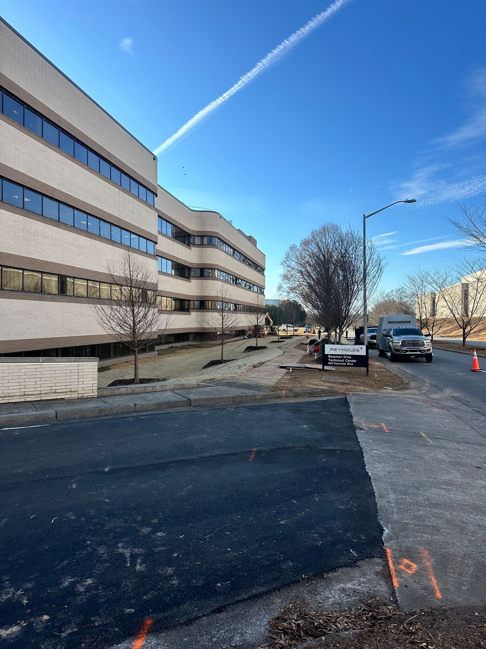 A large building with a lot of windows is sitting next to a road.