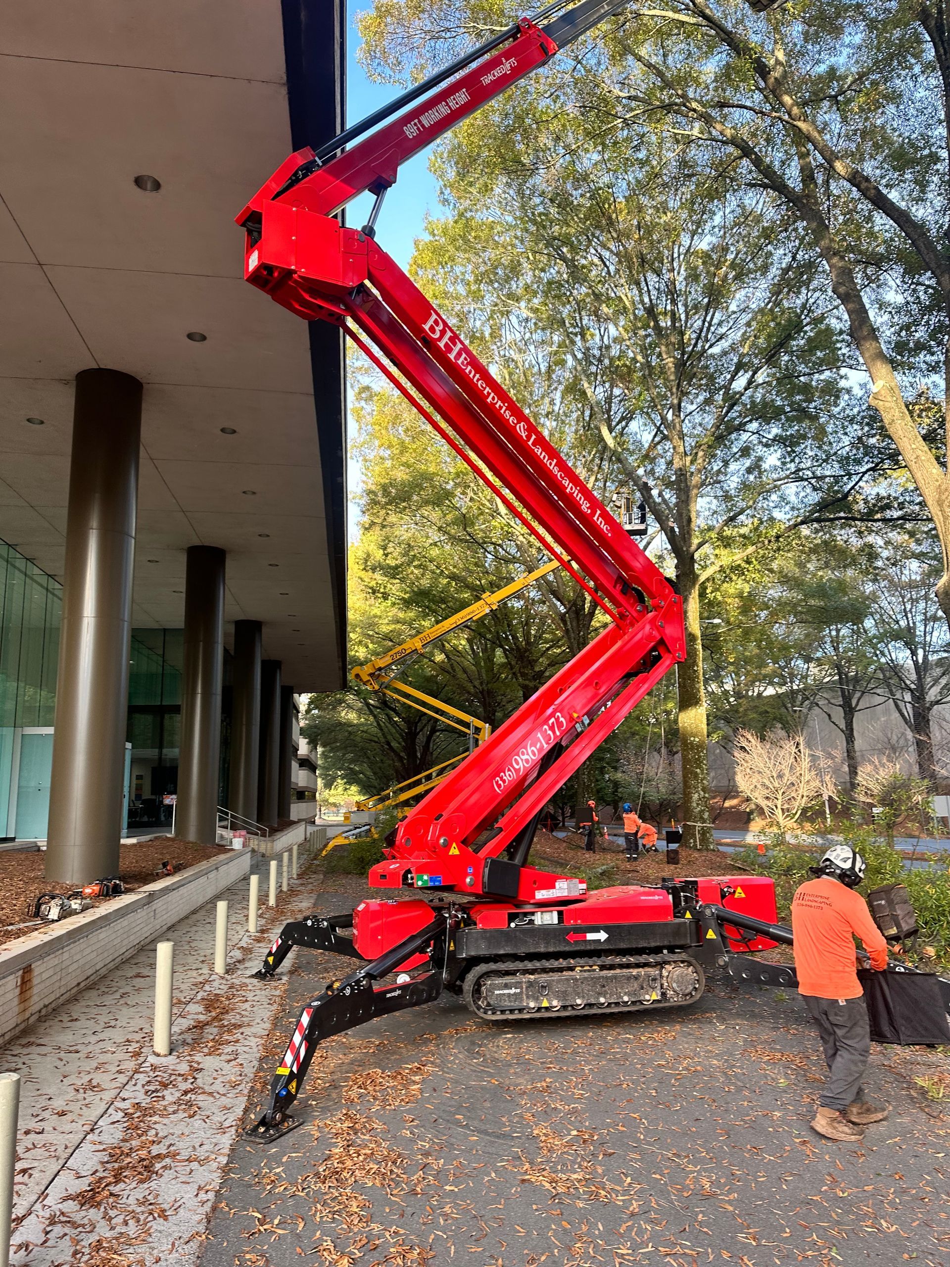 A man is standing next to a red crane in front of a building.