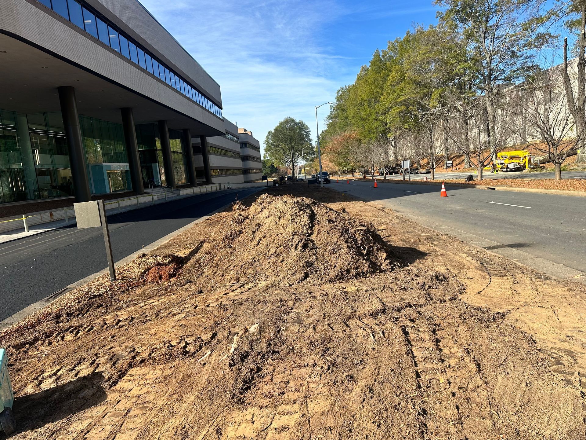 A pile of dirt is sitting on the side of the road in front of a building.